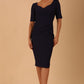 model wearing diva catwalk couture wiltshire fitted pencil-skirt dress with short sleeves and open v-neckline and pleating across the tummy area in navy blue colour front
