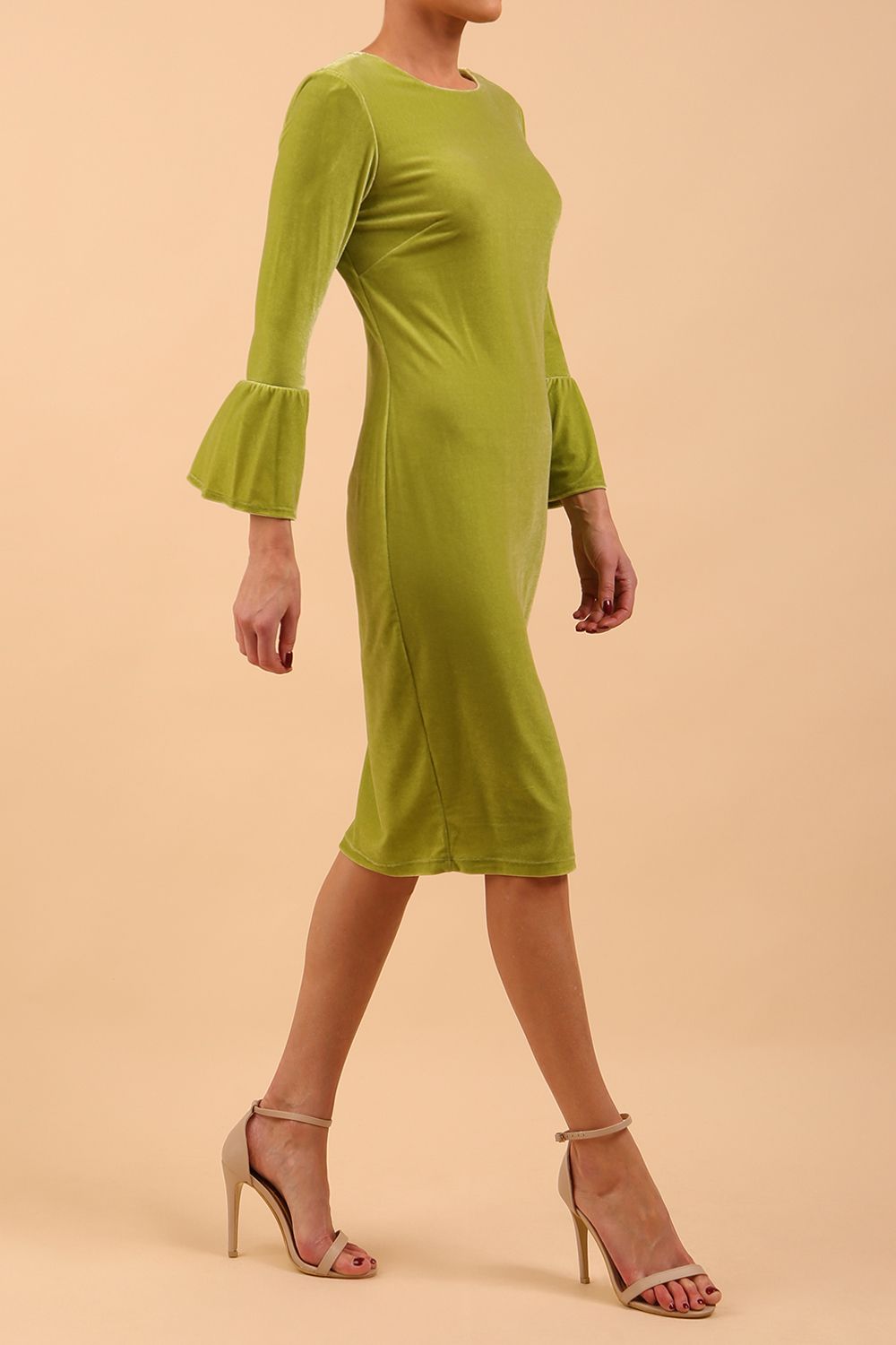A brunette model is wearing a velvet long bell sleeve pencil dress maternity style in tropical green colour front side