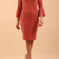 A brunette model is wearing a velvet long bell sleeve pencil dress maternity style in mahogany pink colour front