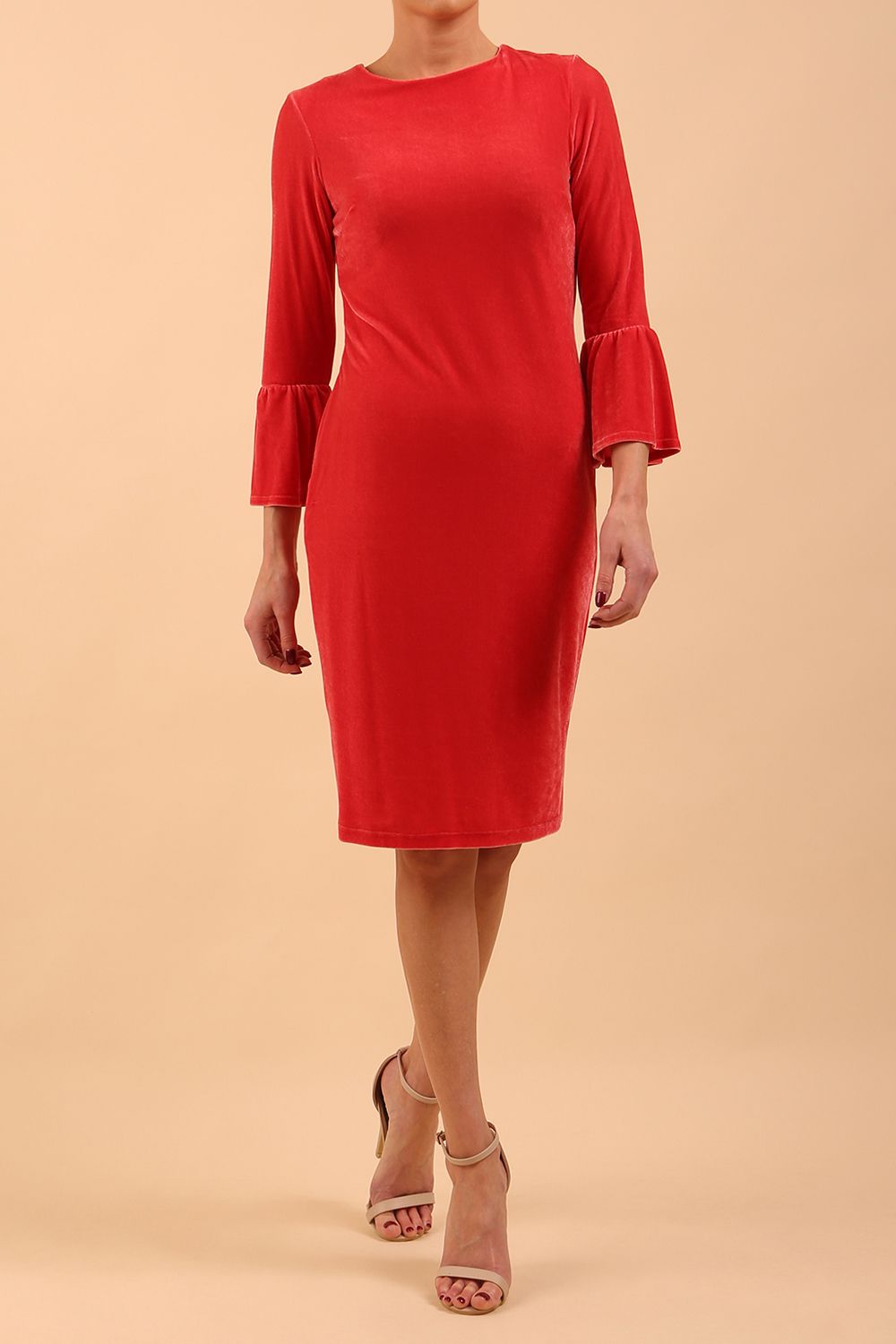 A brunette model is wearing a velvet long bell sleeve pencil dress maternity style in hibiscus red colour front