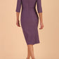 model wearing seed couture royale pencil skirt dress with pleating across the tummy area with rounded neckline with a split in the middle and 3 4 sleeve in Dusky Lilac colour back
