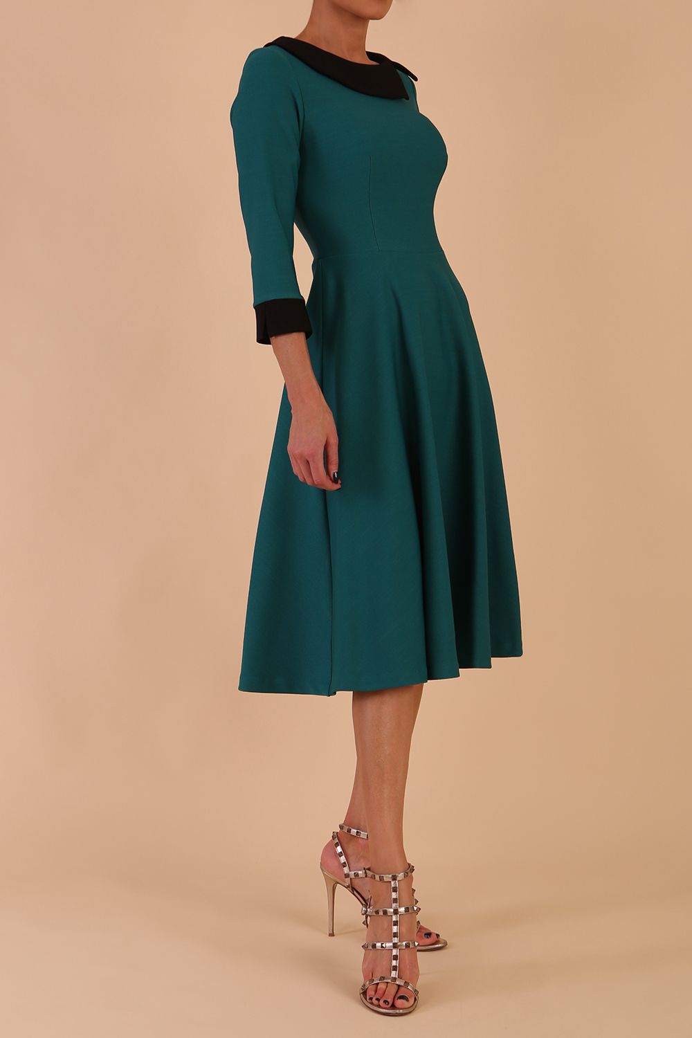 Model wearing Diva catwalk Coralia swing dress in pacific green / black contrast with three quarter sleeve figure fitted front image
