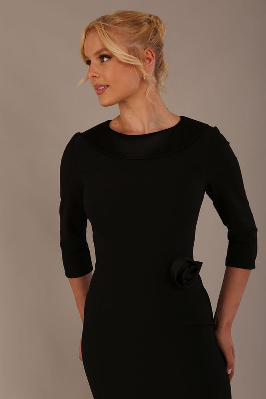 Woman wearing a Heathcote Floral Detail Pencil Dress with a plain background in black close up
