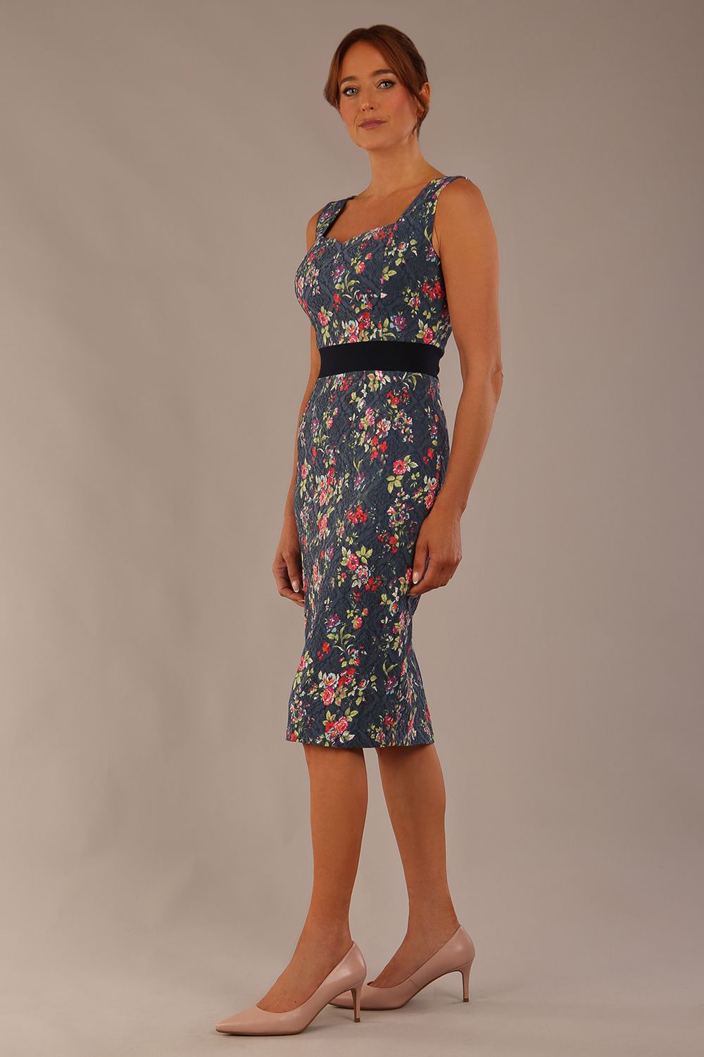 brunette model is wearing a diva catwalk June Floral Sleeveless Navy Waistband Pencil Dress in floral blue print front image