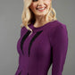 blonde model wearing seed lace purple dress with sleeves and rounded neckline with lace details pointing towards the band