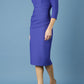 model is wearing diva catwalk seed holsworthy pencil dress with pleating on a tummy area and high neck with sleeves in palace blue front