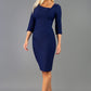 A model is wearing a bistretch pencil three quarter sleeve  and assymetric nackline dress by Diva Catwalk in Navy