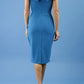 brunette model wearing diva catwalk evening pencil skirt dress sleeveless with lowered neckline and pleating on side in tropic teal colour back