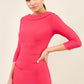 model wearing diva catwalk york pencil-skirt dress with sleeves and rounded folded collar and plearing across the tummy area in yarrow pink colour front