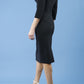 model is wearing diva catwalk quatro sleeved pencil dress with asymmetric wide cut our neckline in black front