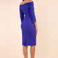 brunette model wearing diva catwalk evening pencil dress off shoulder with sleeves and pleated pencil skirt in colour indigo blue back
