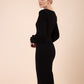 Blonde model wearing Diva Catwalk Praktica long puffed bishop sleeves knee length empire line pencil dress with round neckline with a slit cut in the middle in Black back