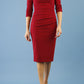 model wearing Diva Catwalk pencil three quarter sleeve dress with a split neckline and pleating across the tummy in merlot red front