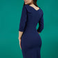 A brunette model is wearing a round neckline pencil dress with pleating on the tummy area in navy back image