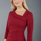 model is wearing a red pencil three quarter sleeve dress with assymetric neckline and pleating around tummy area front image wine colour