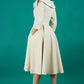 Brunette model is wearing a sleeved beige oversized collar swing dress with button detail at the front and pockets in the skirt back photo