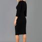 A blonde model is wearing a 3/4 sleeve pencil dress with the keyhole details in black