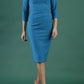 brunette model is wearing diva catwalk pencil dress with collar and a button detail on a side with 3/4 sleeve in mosaic blue front