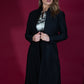 brunette model wearing diva catwalk couture fine raquella coat with buttons across the front and long sleeves with high neck and pockets in black colour front