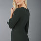 A blonde model is wearing a 3/4 sleeve pencil dress with the keyhole details in green back image