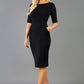Blonde model is wearing a sleeved pencil dress with round neckline in black with pockets in the skirt front image