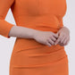 brunette model wearing diva catwalk best selling lydia pencil sleeved dress with slit at the neckline and pleating across the tummy in colour sun orange front