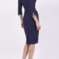 blonde model wearing seed tuscany pencil fitted dress in navy blue colour with a split in the neckline and split detail on sleeves back