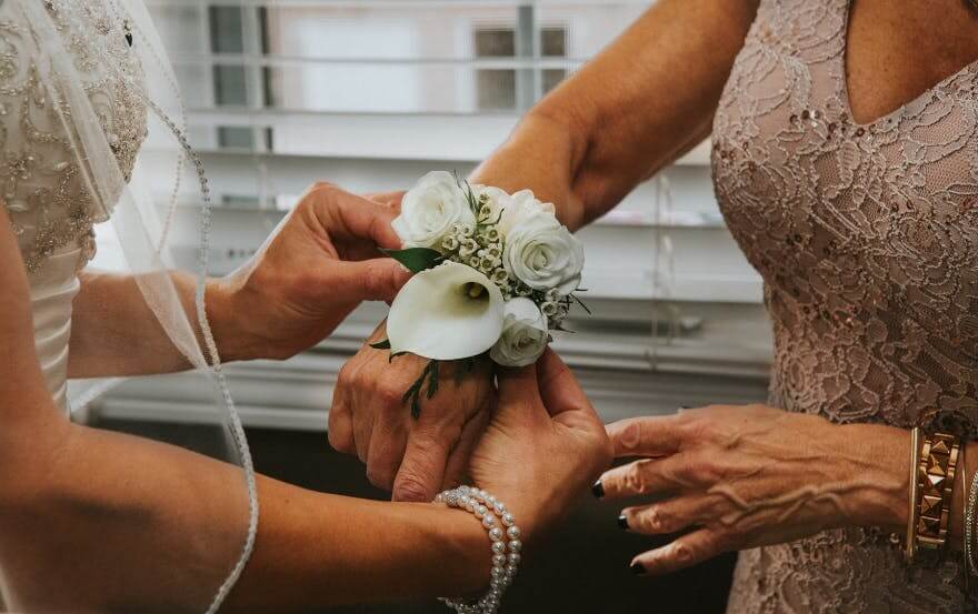bride putting flowers on her mother's wrist 