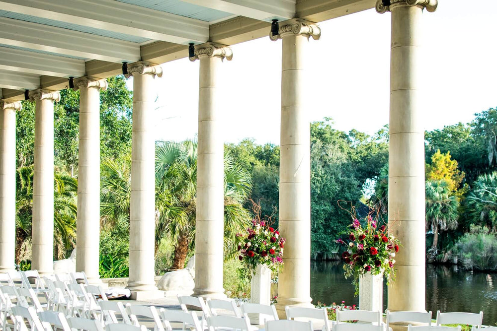 Photograph of a wedding reception with a long table and pillars overlooking a lake 