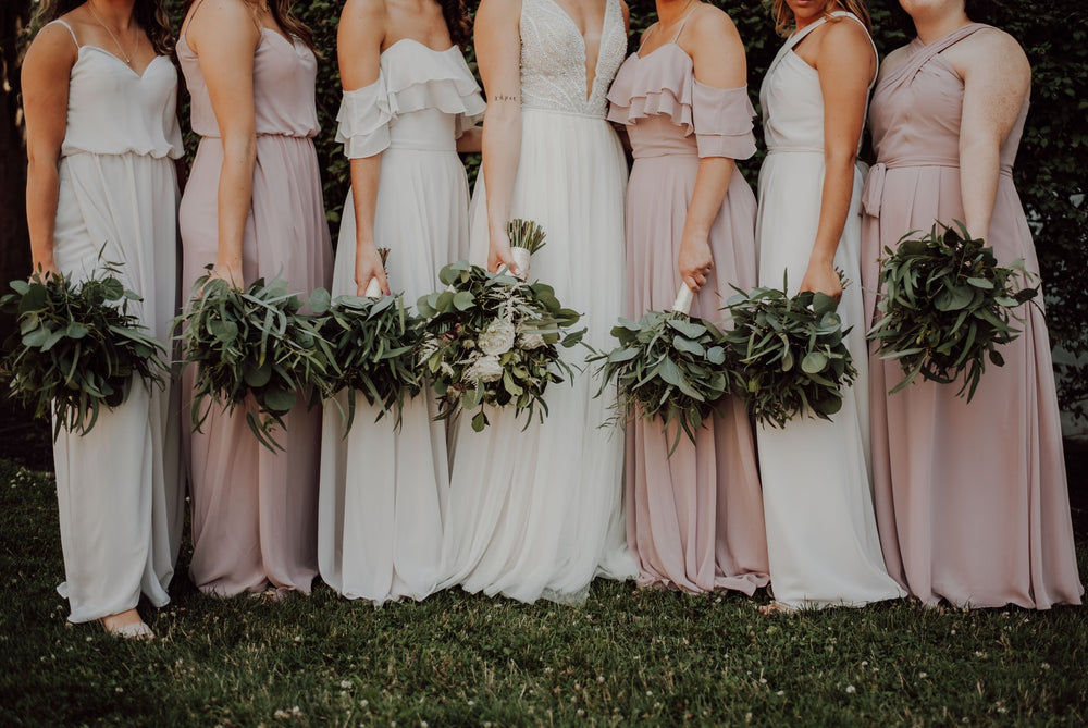 bride and bridesmaids in dresses holding flowers 