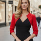 A woman wearing a red cropped bolero jacket with 3/4 sleeves and black clothing underneath. 