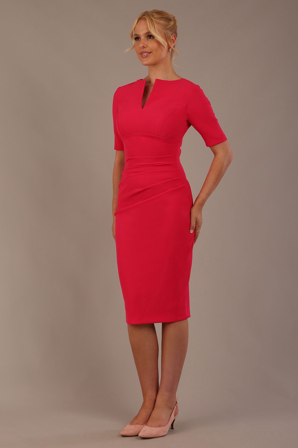 blonde model is wearing diva catwalk lydia short sleeve pencil fitted dress in paradise pink colour with rounded neckline with a slit in the middle front