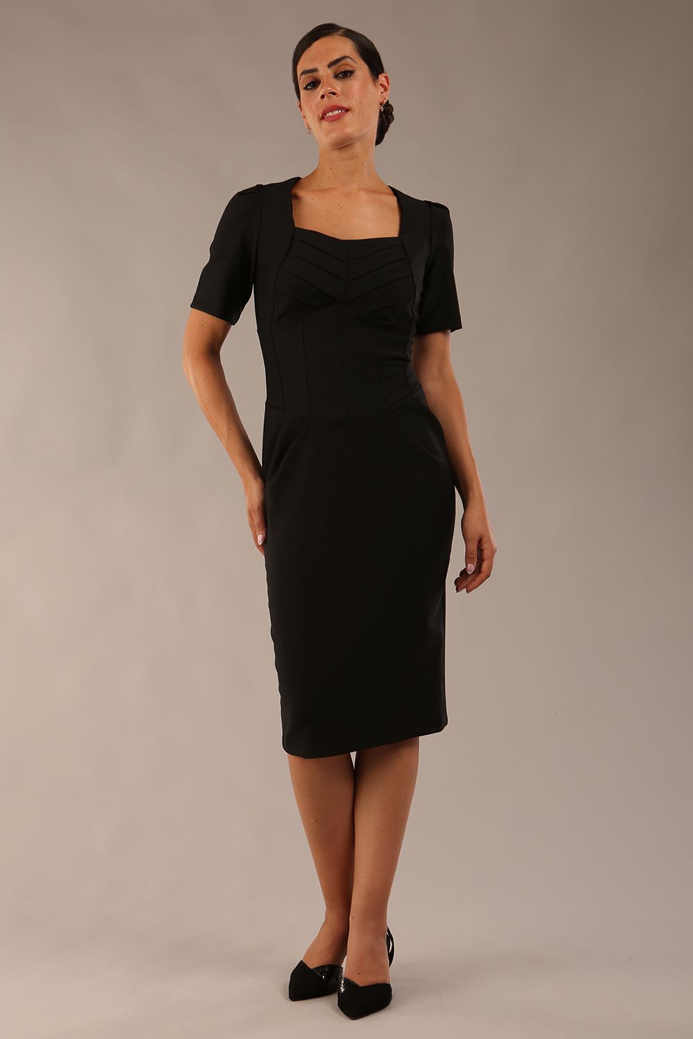 model wearing seed belgravia square neckline pencil dress with short pleated sleeves and folded pleating at the front in black colour