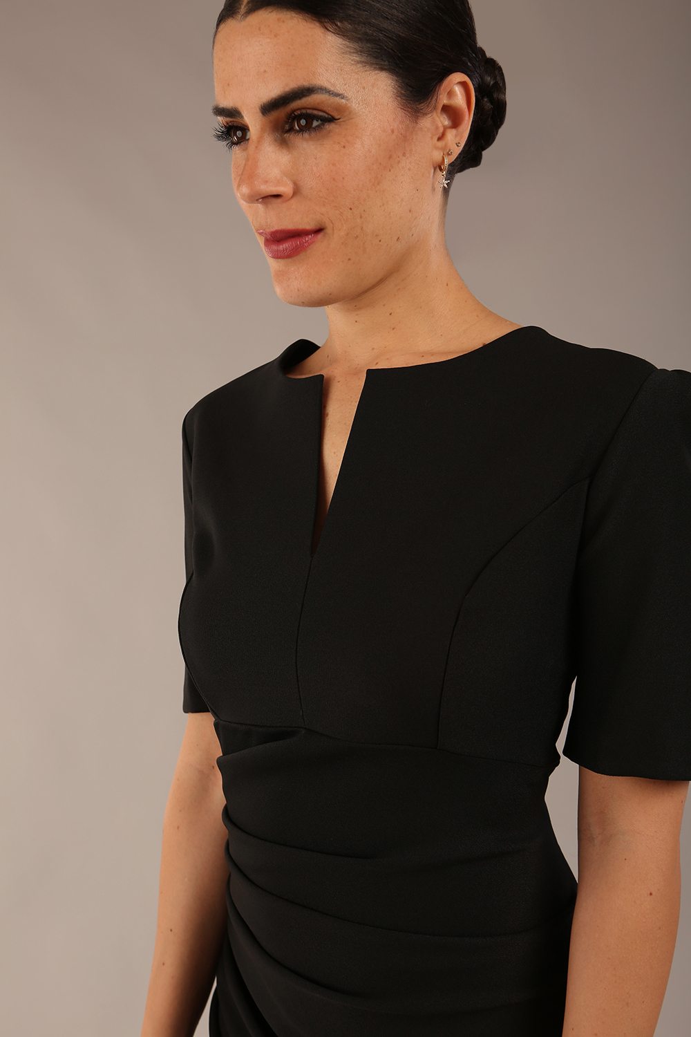Brunette Model is wearing a pencil short sleeve seed Fitzrovia dress round sleeves with v-slit knee length in black colour front image