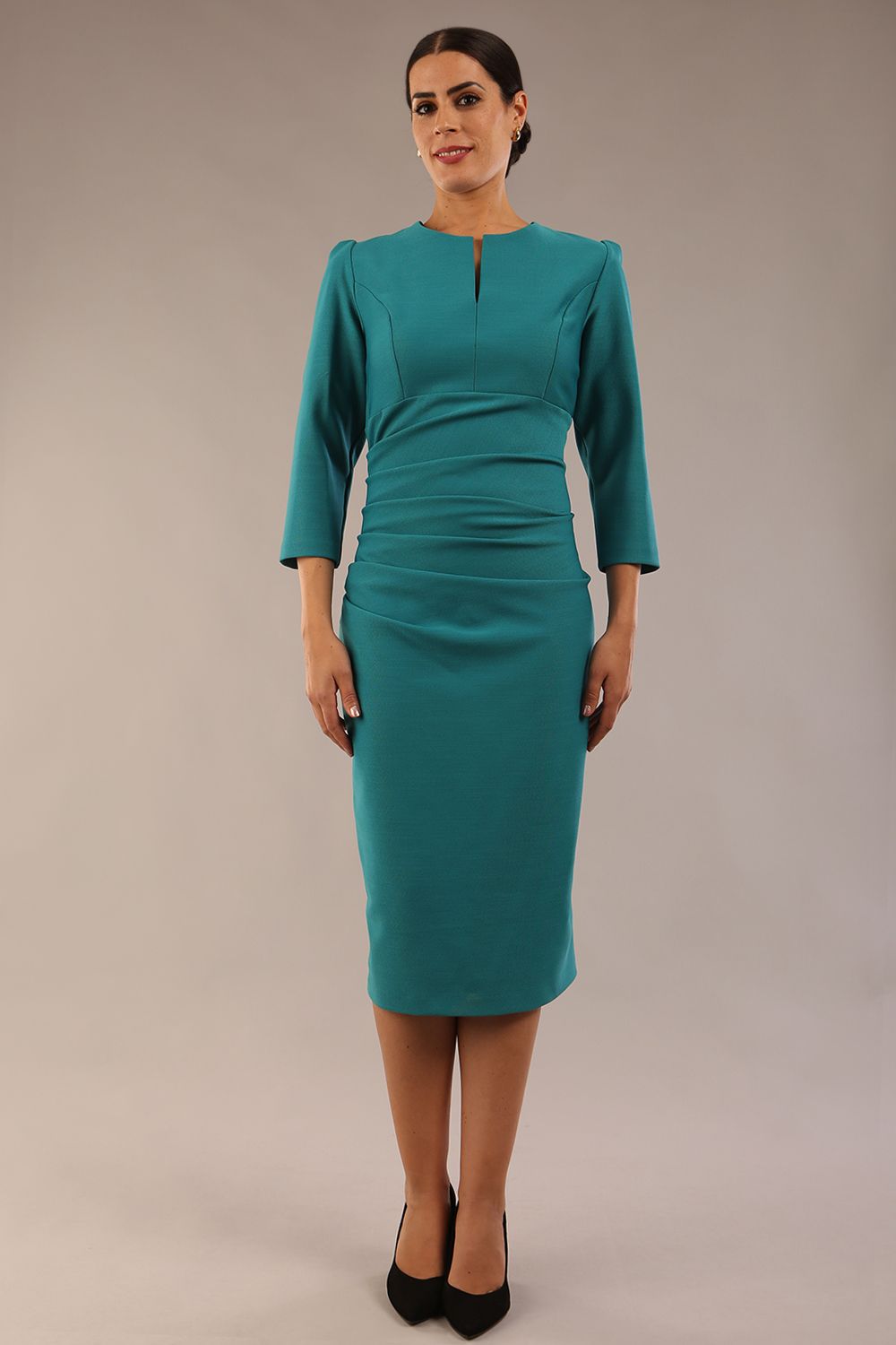 model is wearing a diva catwalk seed fitzrovia 3/4 sleeve pencil dress with round neckline and v-slit and pleating details on the skirt in harbour green front