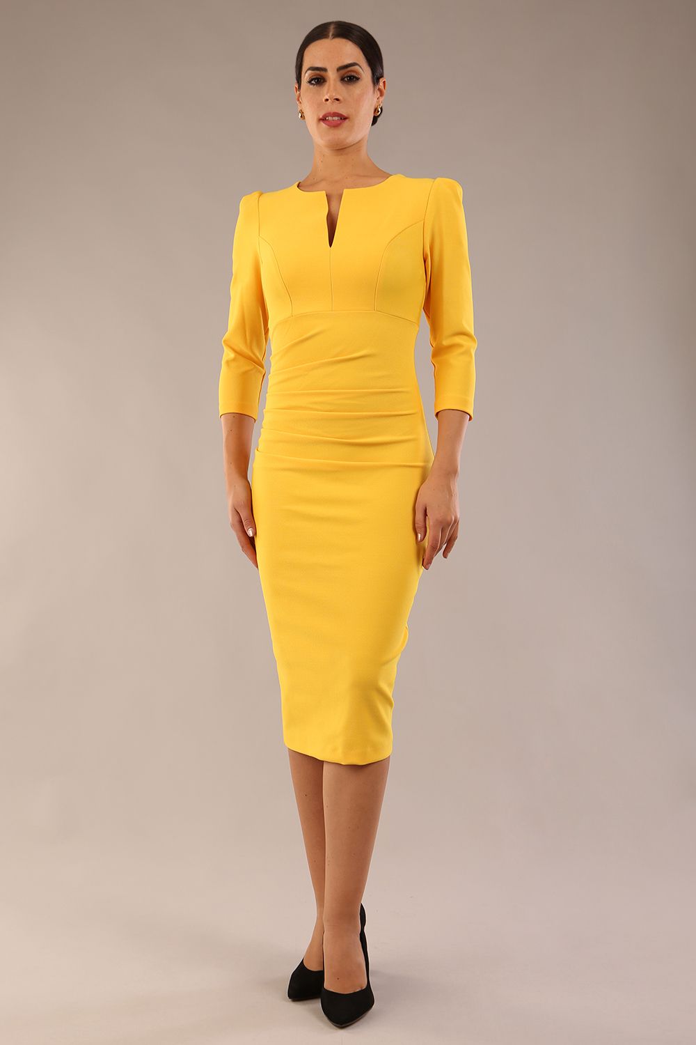 model is wearing a diva catwalk seed fitzrovia 3/4 sleeve pencil dress with round neckline and v-slit and pleating details on the skirt in daffodil yellow front