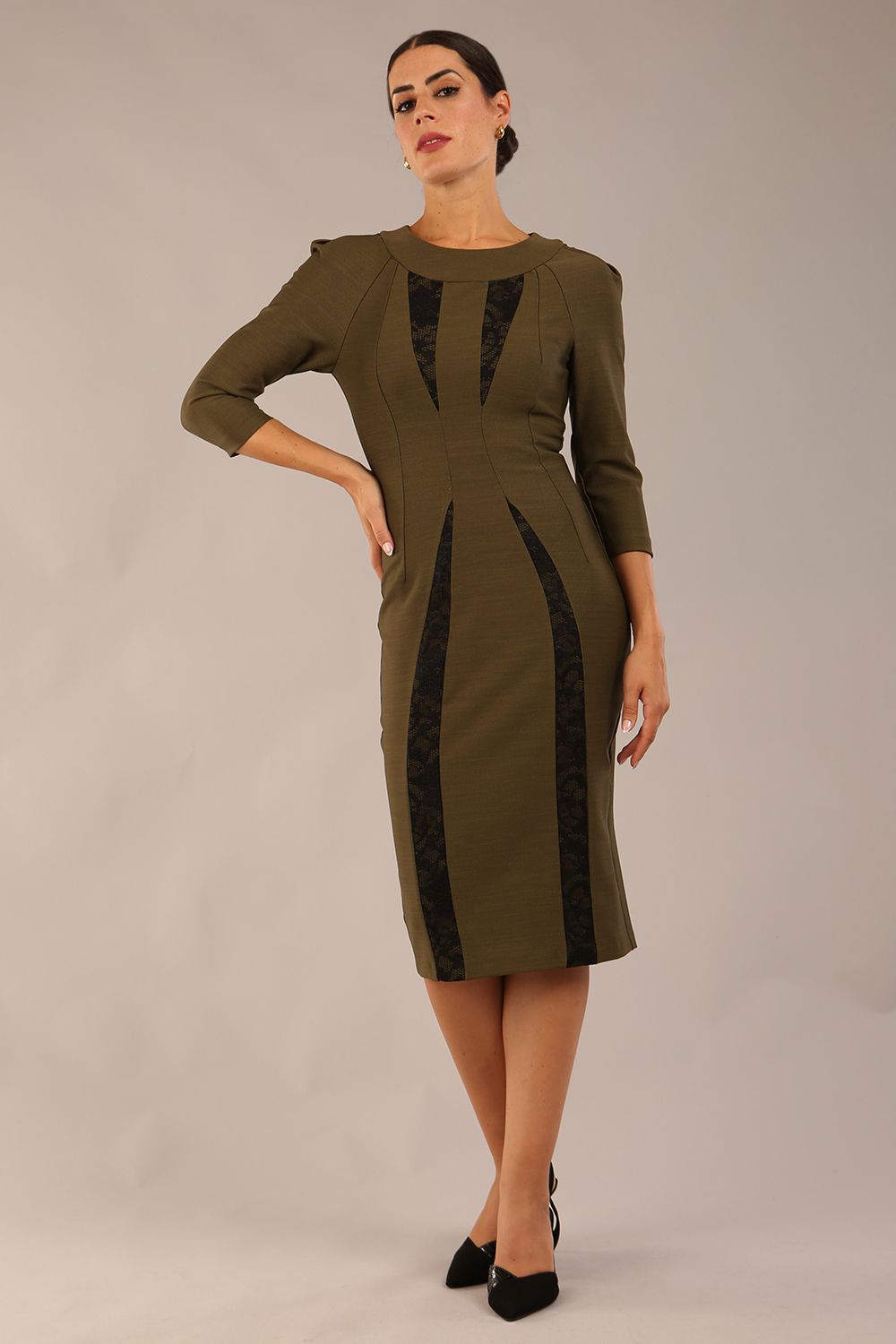 model wearing seed bertie dress with sleeves and rounded neckline with lace details pointing towards the band in olive green front