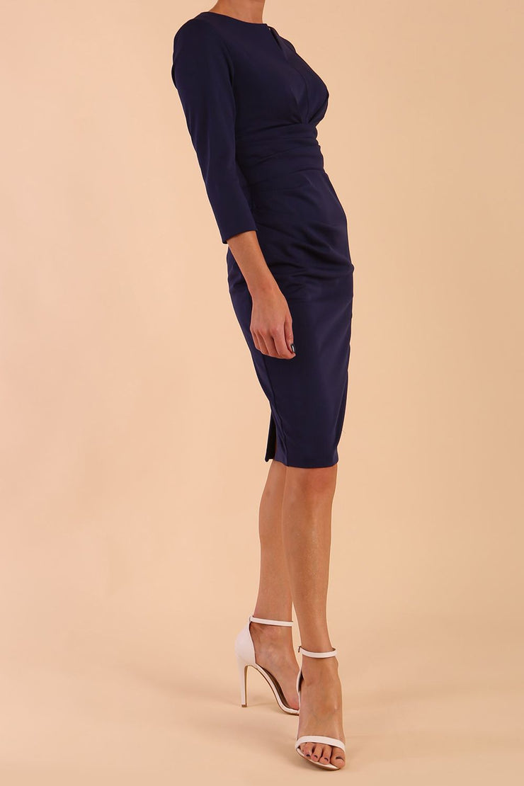 model wearing diva catwalk donna pencil dress with wide band and sleeves and rounded neckline with low split in navy blue colour front side
