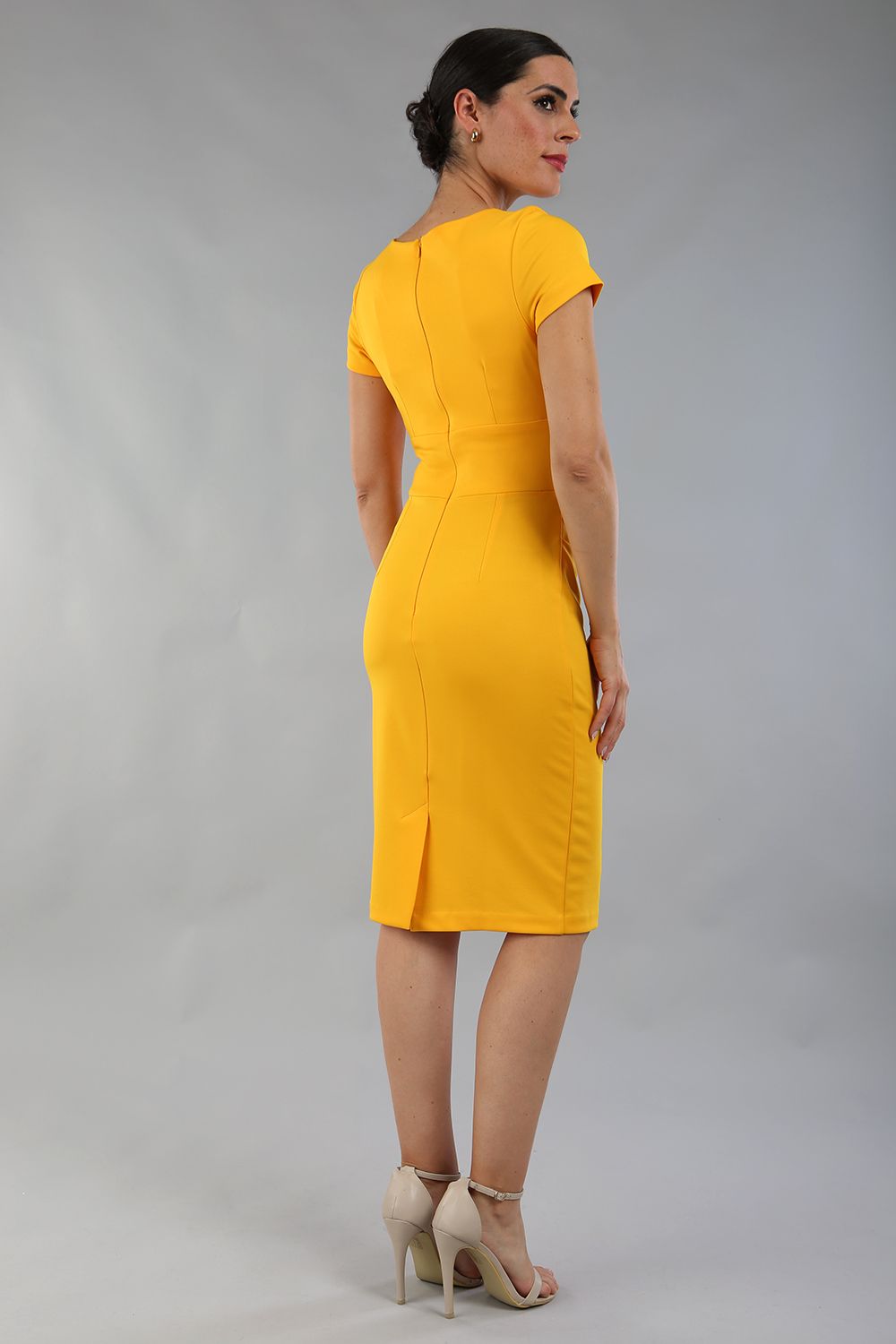 Model wearing Diva Catwalk Donna Short Sleeve Pencil Dress with a wide band and pleating across the tummy area in Saffron Yellow back