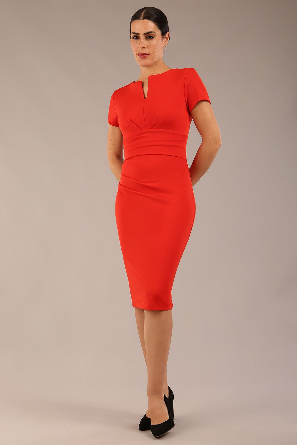 Brunette Model wearing a Diva Catwalk Donna Short Sleeve Pencil Dress with a wide band and pleating across the tummy area and round neckline with v-slit in Burnt Orange front image