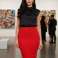 Woman in black top and red skirt standing in an art gallery.
