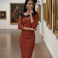 model is wearing diva catwalk pencil dress with contrasting asymmetric satin neckline in marsala brown front with black accents standing in an art gallery.