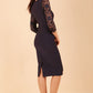 Brunette Model is wearing seed couture lace pencil dress by diva catwalk in black back side