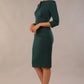 Model wearing the Diva Daphne ¾ Sleeved dress with pleat detail across the hips and ¾ sleeve length in forest green front side