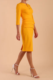 Model wearing the Diva Daphne ¾ Sleeved dress with pleat detail across the hips and ¾ sleeve length in saffron yellow side