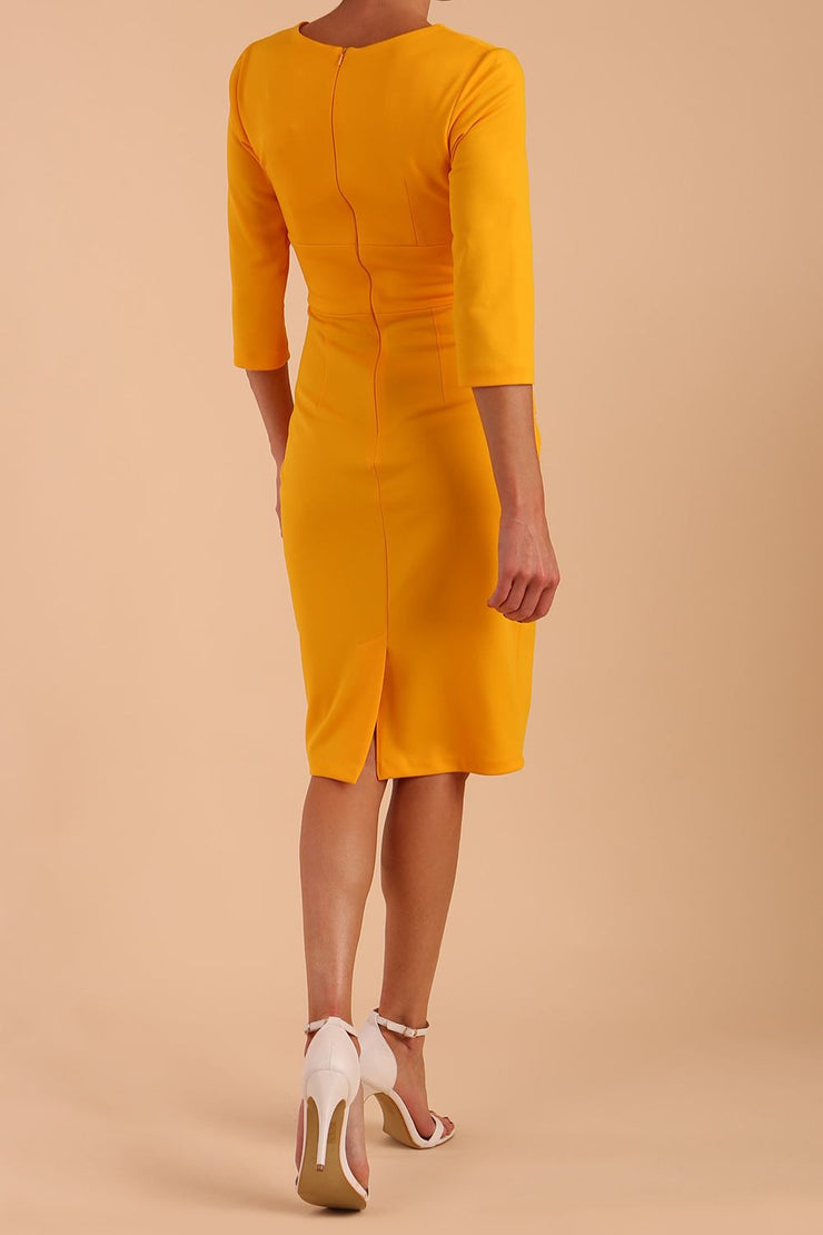 Model wearing the Diva Daphne ¾ Sleeved dress with pleat detail across the hips and ¾ sleeve length in saffron yellow back