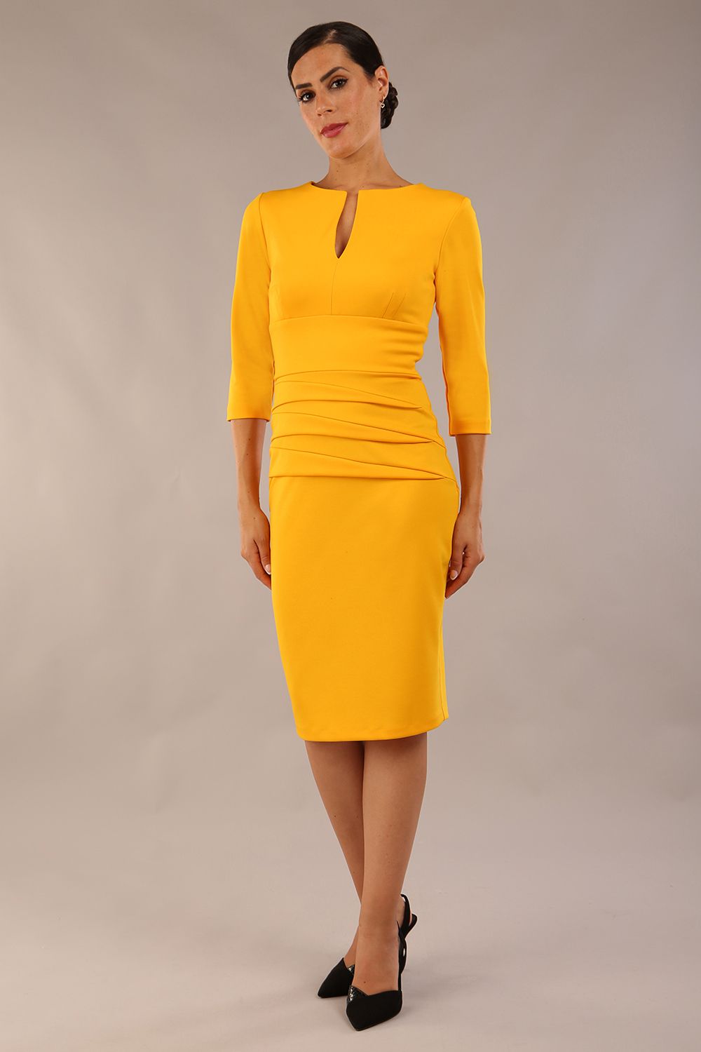 Model wearing the Diva Daphne ¾ Sleeved dress with pleat detail across the hips and ¾ sleeve length in saffron yellow front