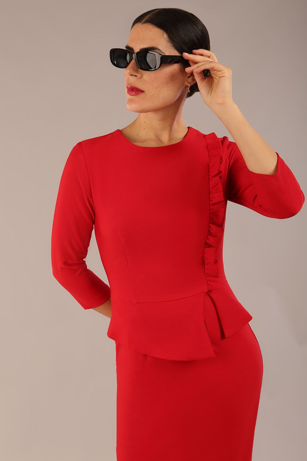 Brunette Model is wearing a three quarter sleeve couture seed pencil dress frill side detail by Diva Catwalk in salsa red