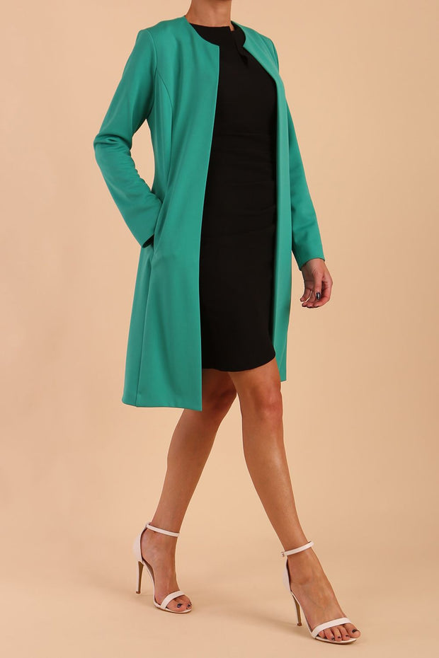 model wearing diva catwalk teal coat with long sleeves and a belt in Emerald Green side