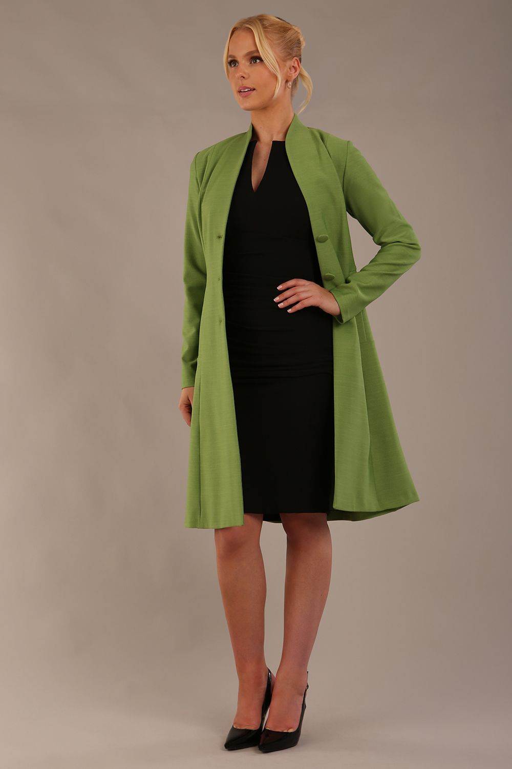 blonde model wearing diva catwalk couture fine raquella coat with buttons across the front and long sleeves with high neck and pockets in citrus green colour front (Citrus Green)